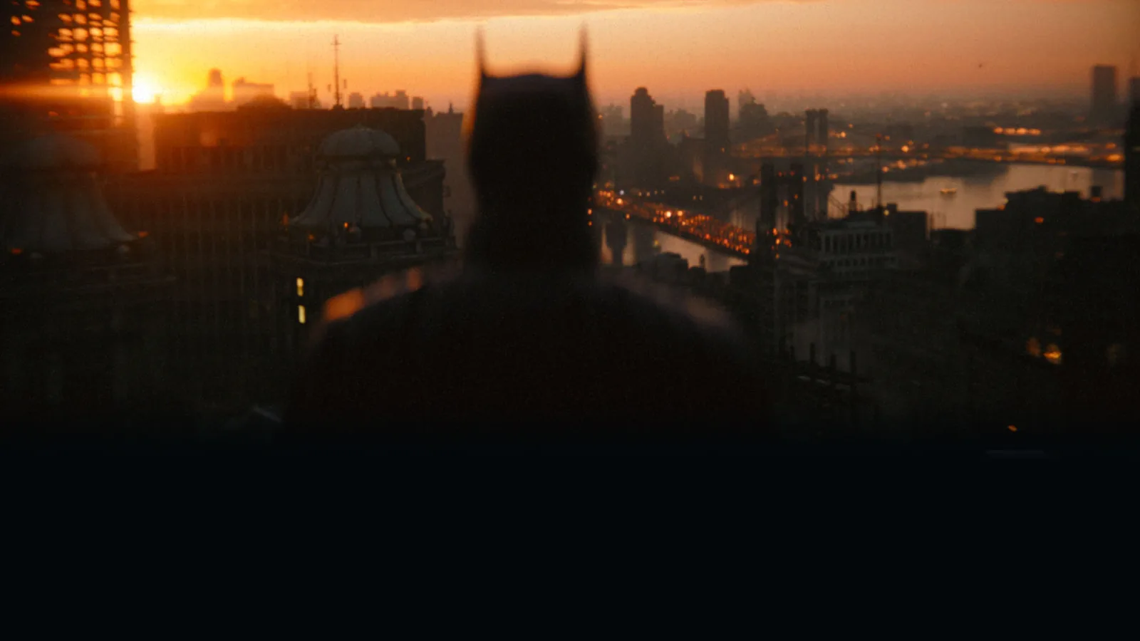 Batman observa o horizonte de Gotham ao pôr do sol em The Batman, de Matt Reeves.