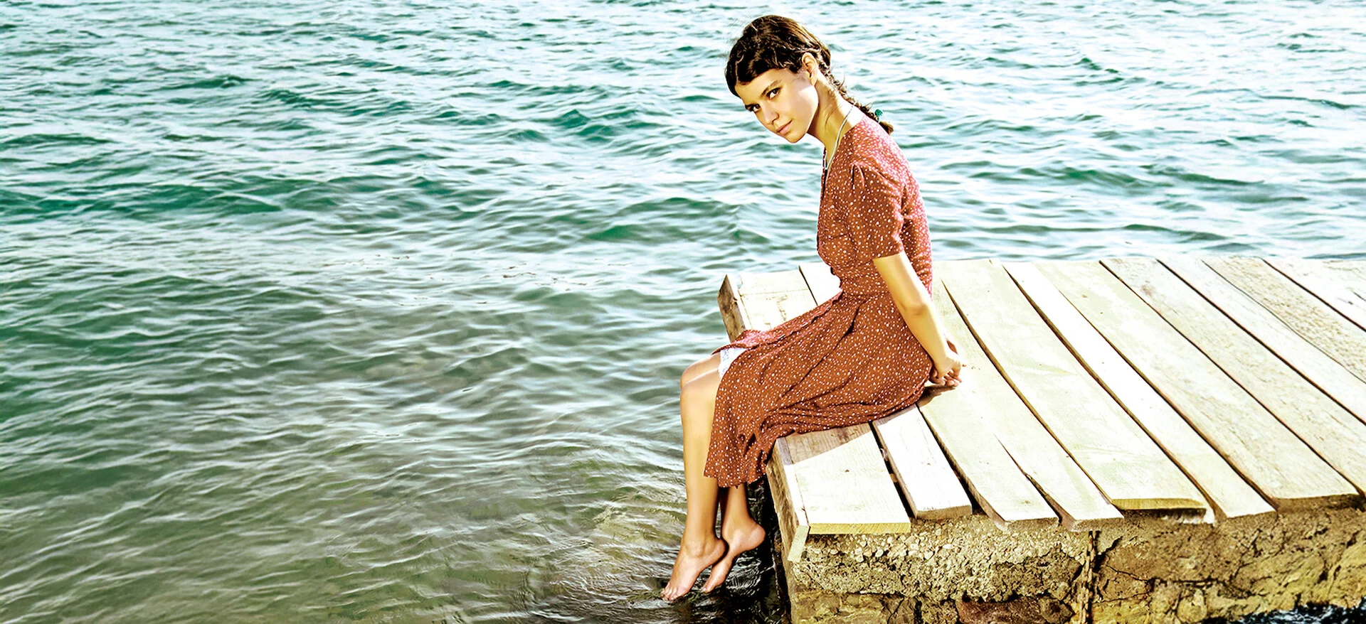 Fatmagül, interpretada por Beren Saat, sentada próxima ao mar