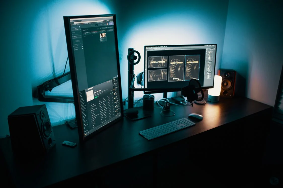 Setup com dois monitores presos em braços articulados sobre uma mesa