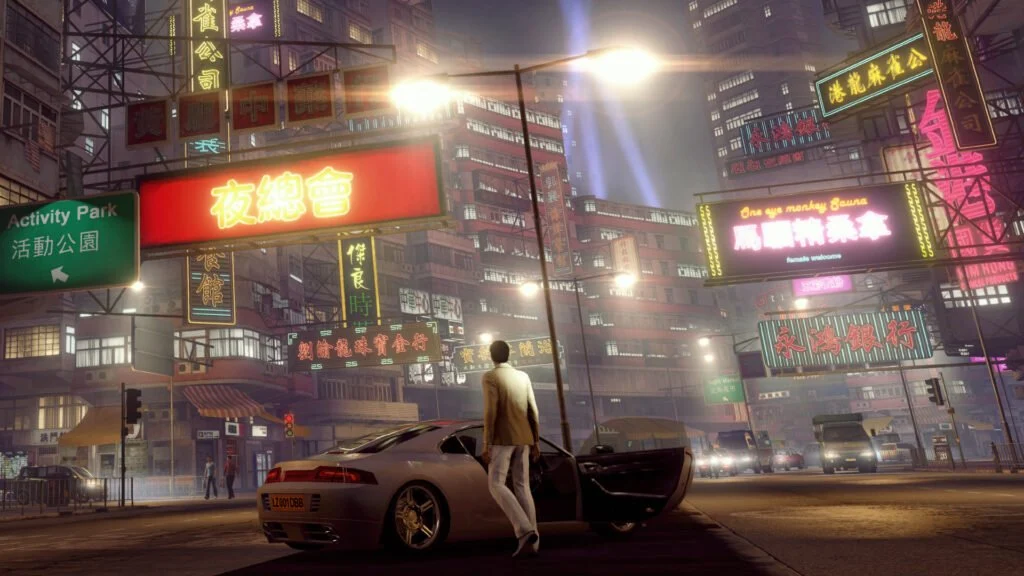 Wei Shen ao lado de carro nas ruas iluminadas de Hong Kong em Sleeping Dogs