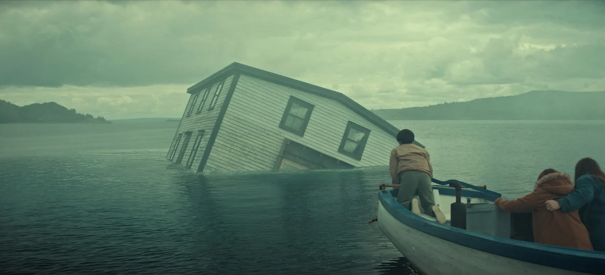 Casa parcialmente submersa diante de um barco em cena da minissérie Profundezas