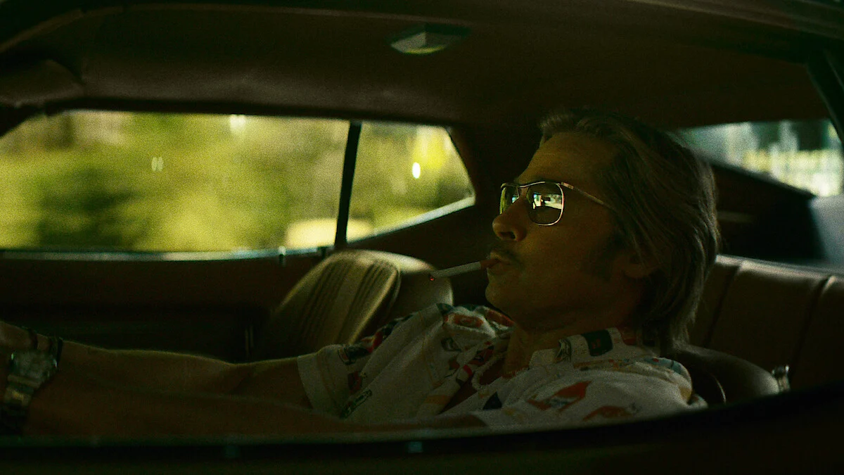 Brad Pitt como Cliff Booth dirigindo um carro em The Further Mis-Adventures of Cliff Booth