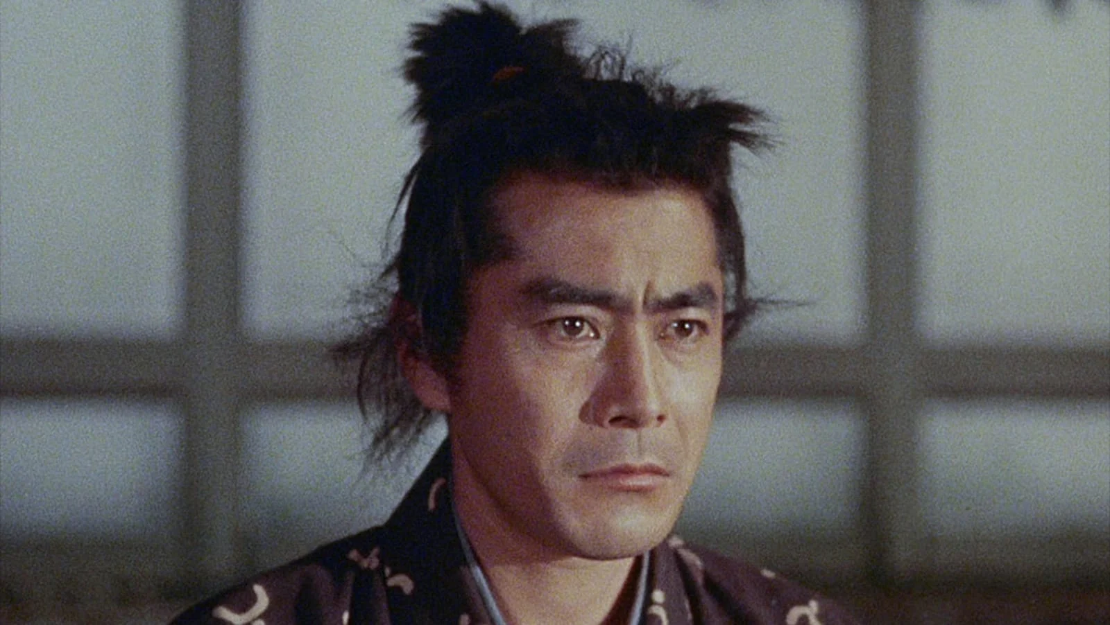 Toshirō Mifune como Miyamoto Musashi na Trilogia Samurai, com cabelo preso e expressão séria.
