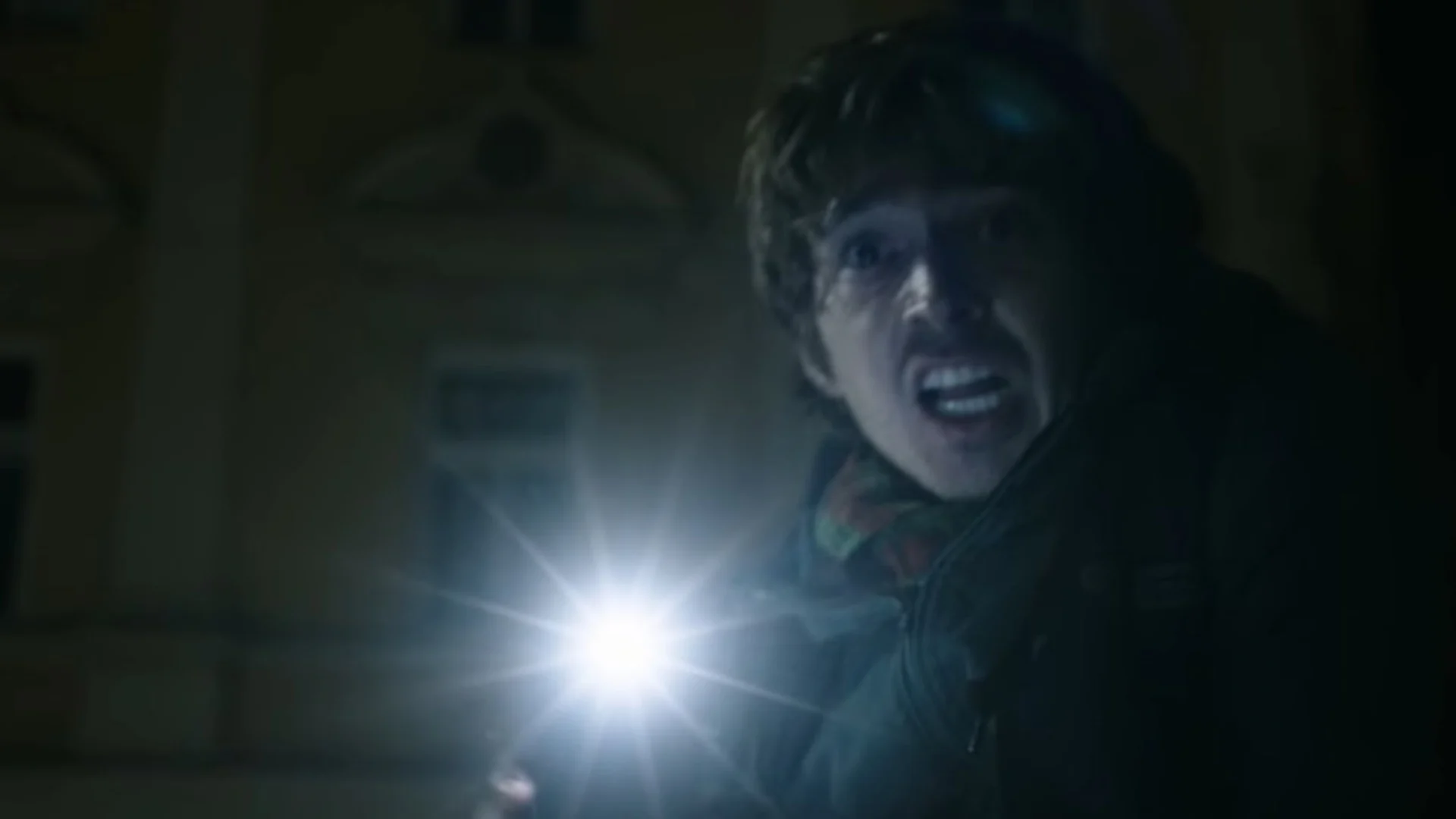 Bryan usa uma lanterna durante uma cena escura de Resident Evil