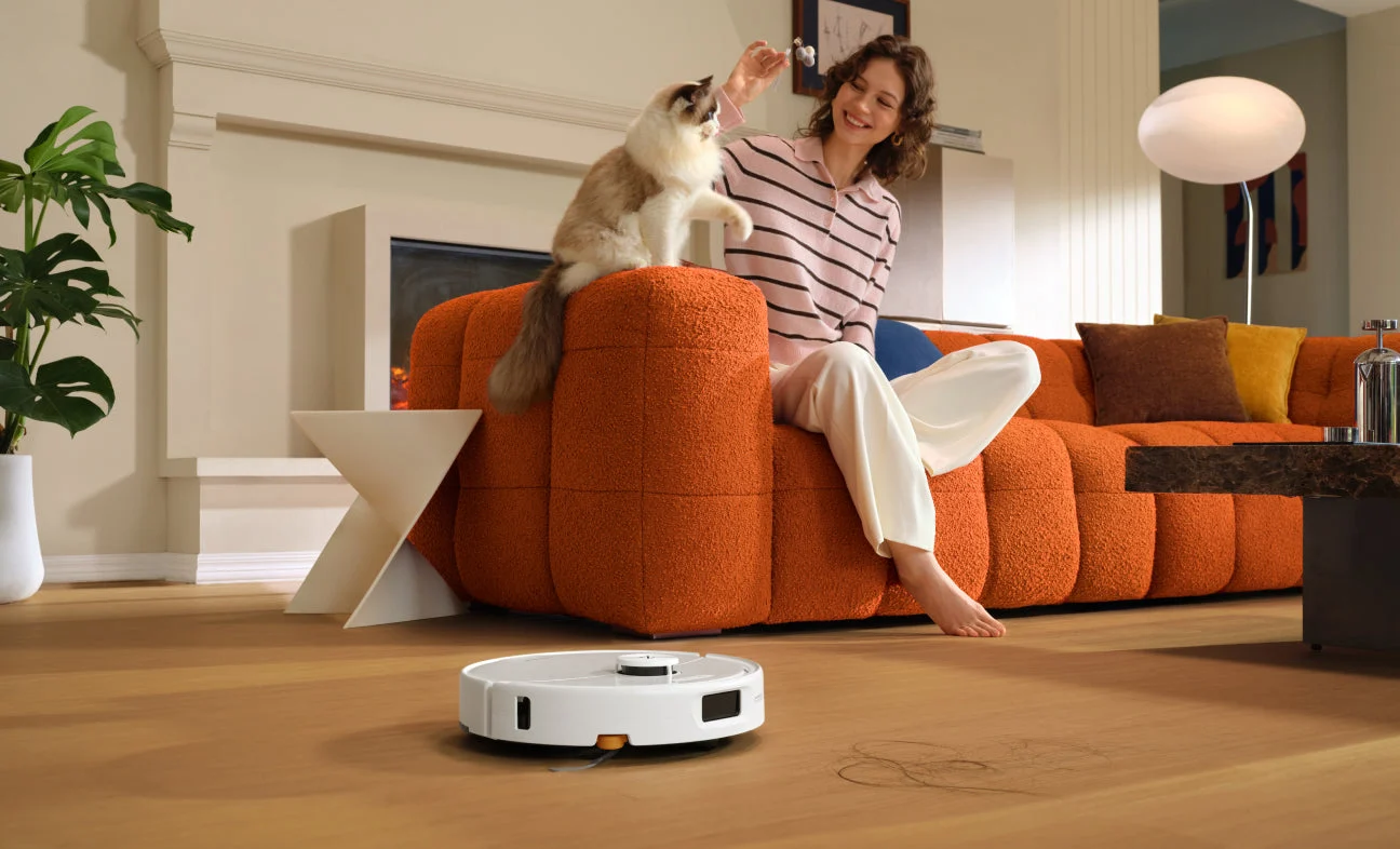 Roborock Qrevo 2 Pro branco limpando o piso de uma sala com um gato ao fundo