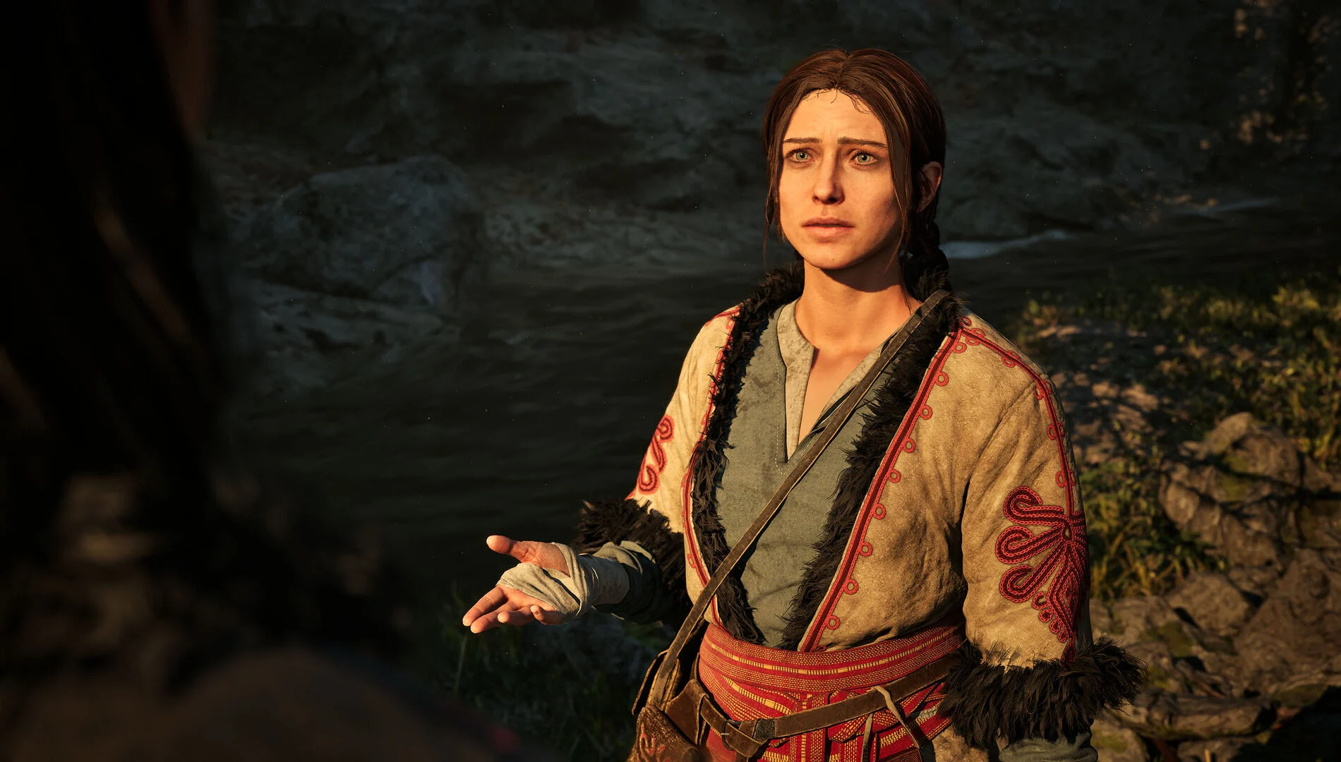Moradora conversa com Coen perto de um rio em The Blood of Dawnwalker
