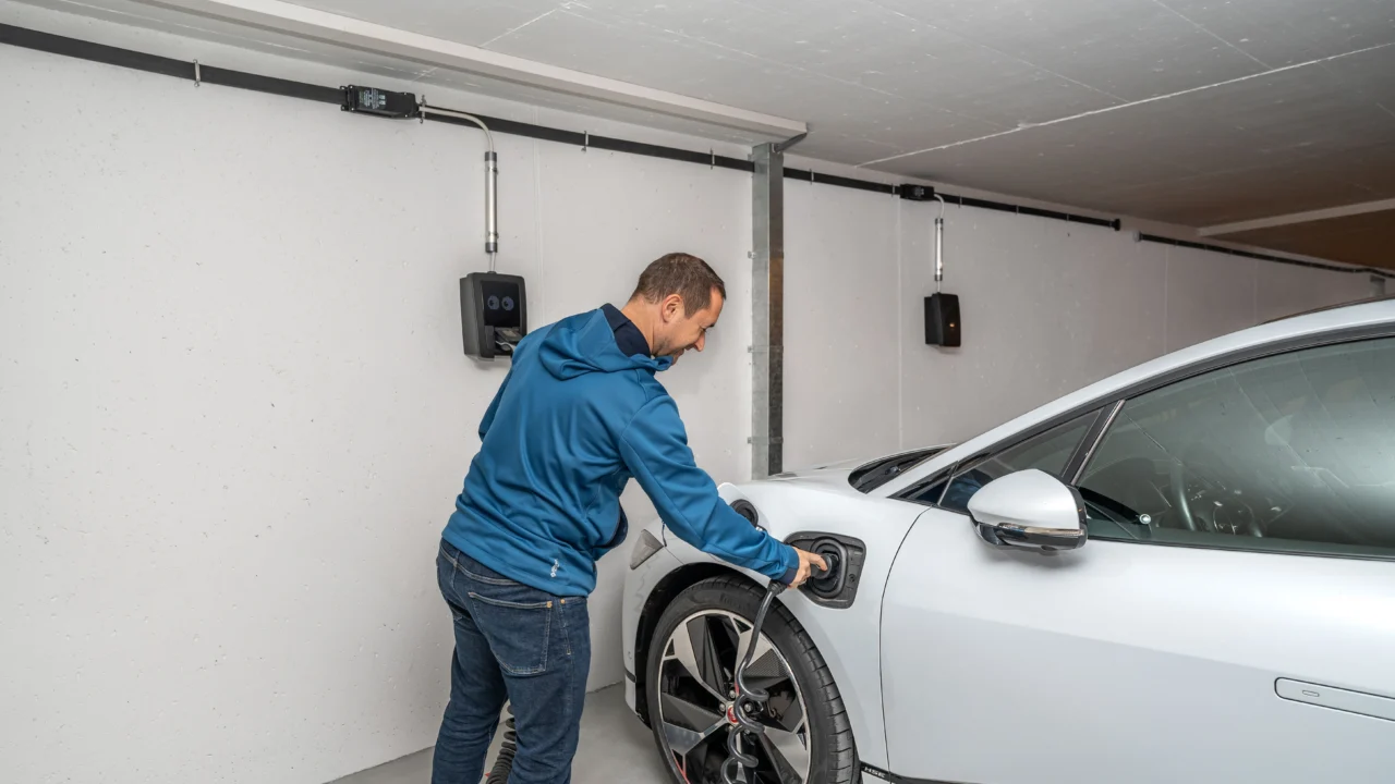 Carro elétrico sendo conectado a carregador instalado em garagem residencial
