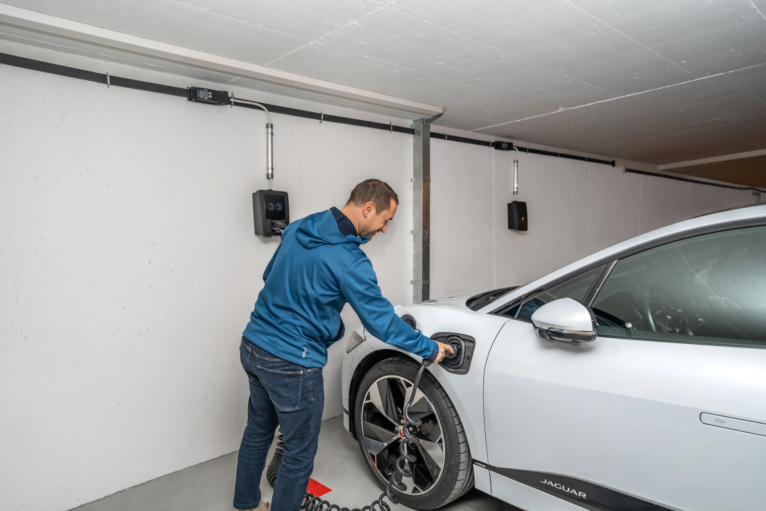 Carro elétrico sendo conectado a carregador instalado em garagem residencial