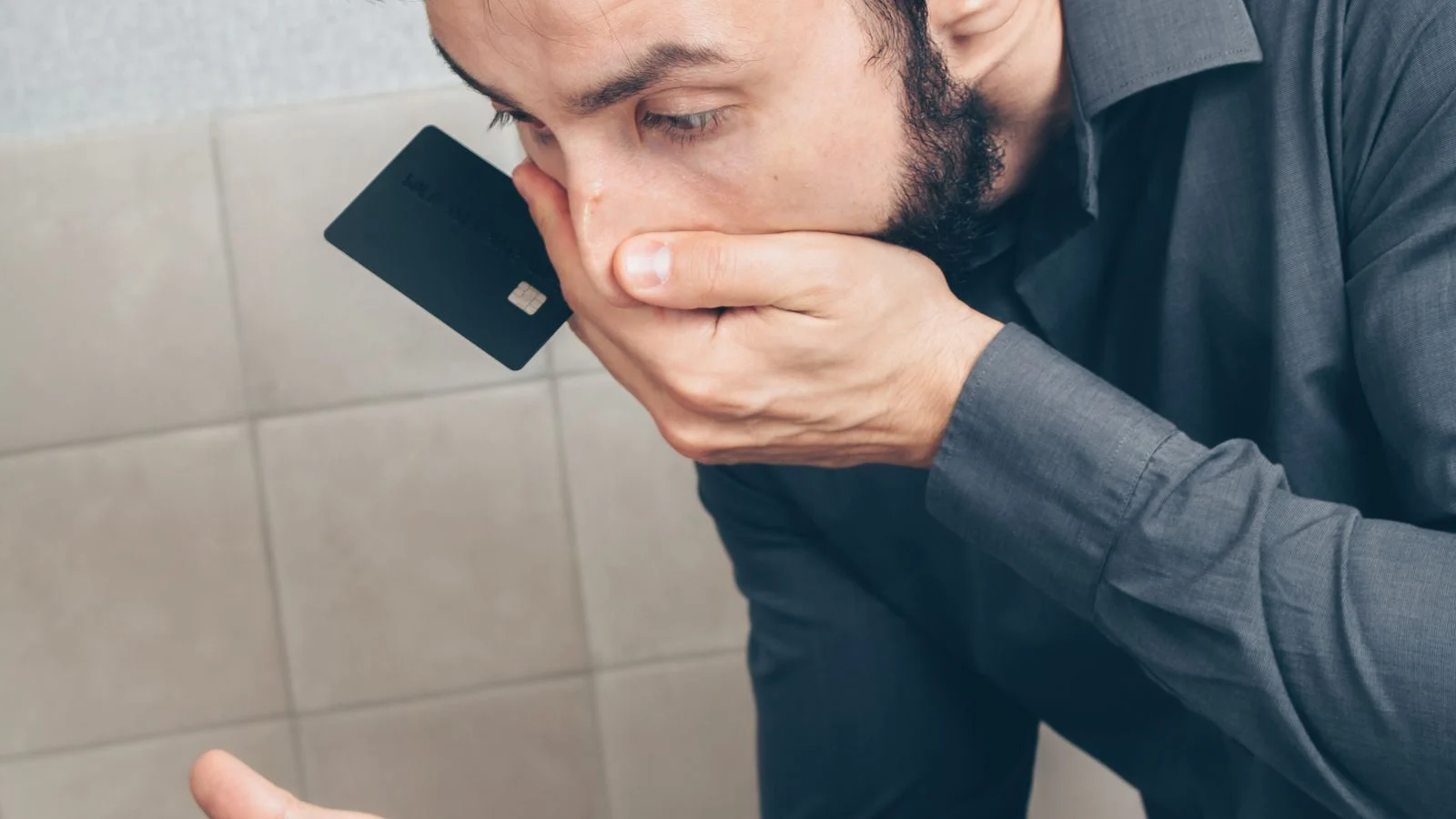 Pessoa preocupada olhando para um smartphone enquanto segura um cartão