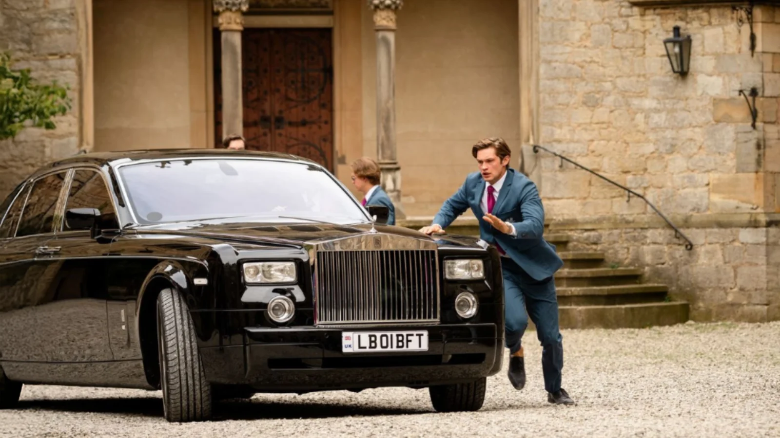 James Beaufort corre ao lado de um carro em frente a Maxton Hall na terceira temporada