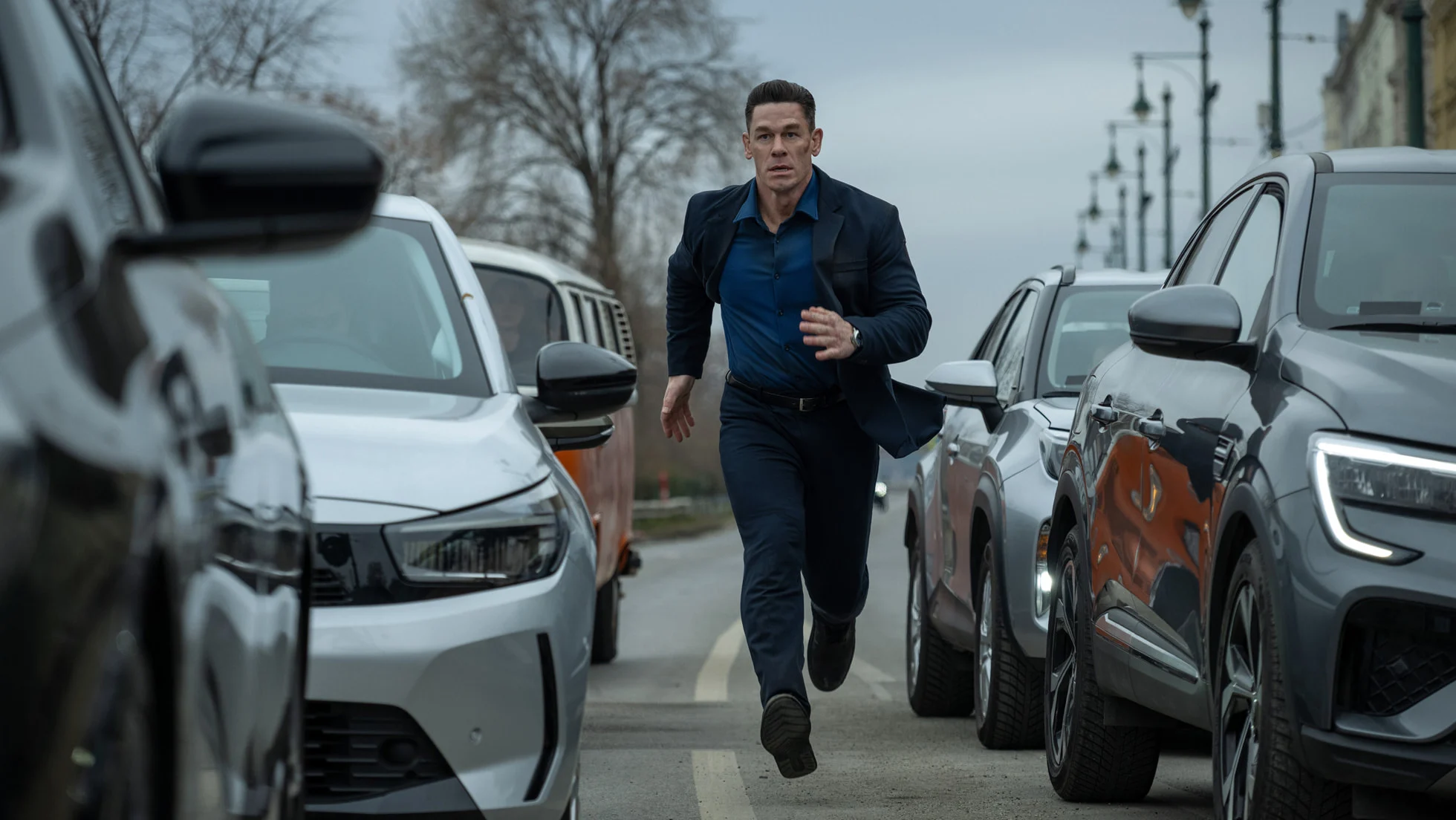 John Cena como Sean correndo entre carros durante uma perseguição em Matchbox – O Filme