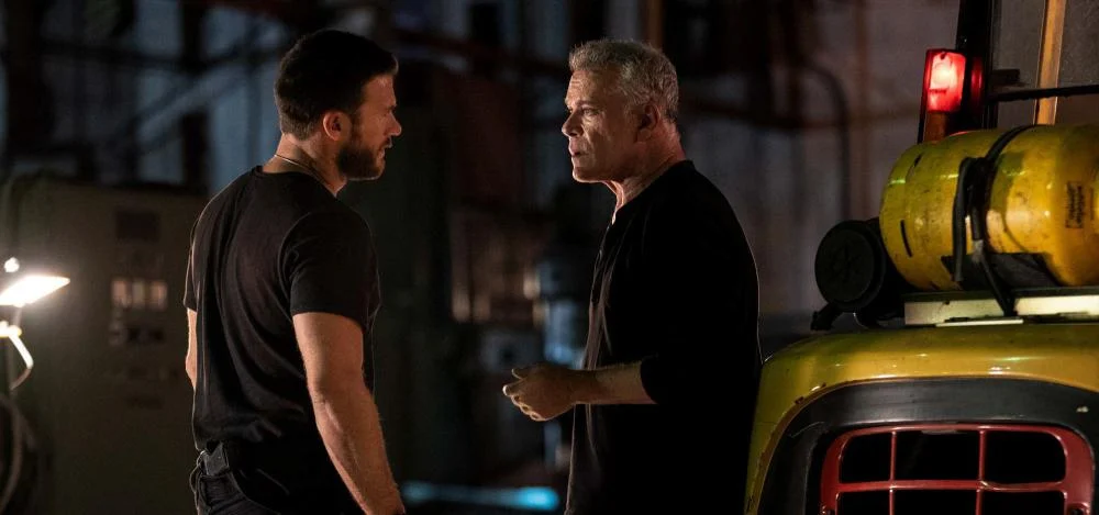 Scott Eastwood e Ray Liotta interpretam Riggin e Lowell durante uma discussão ao lado de uma empilhadeira no filme 1992