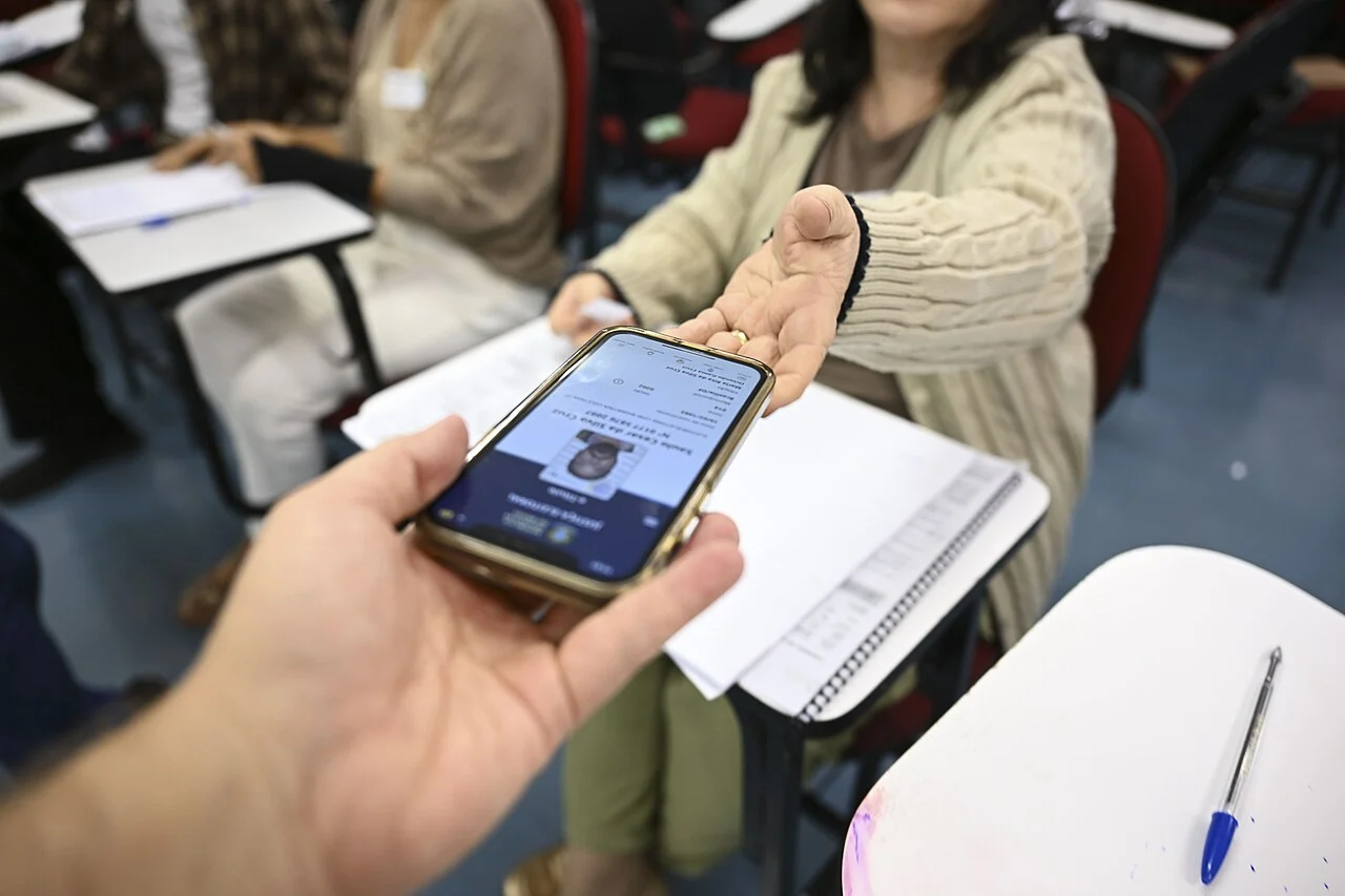 Eleitor apresenta aplicativo e-Título durante atendimento em seção eleitoral no primeiro turno das Eleições 2026