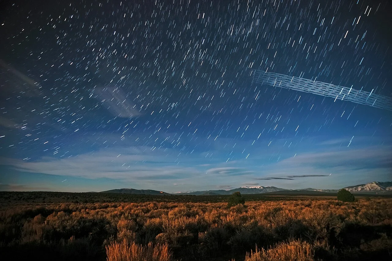 Trilhas luminosas de satélites Starlink em fotografia de longa exposição do céu noturno