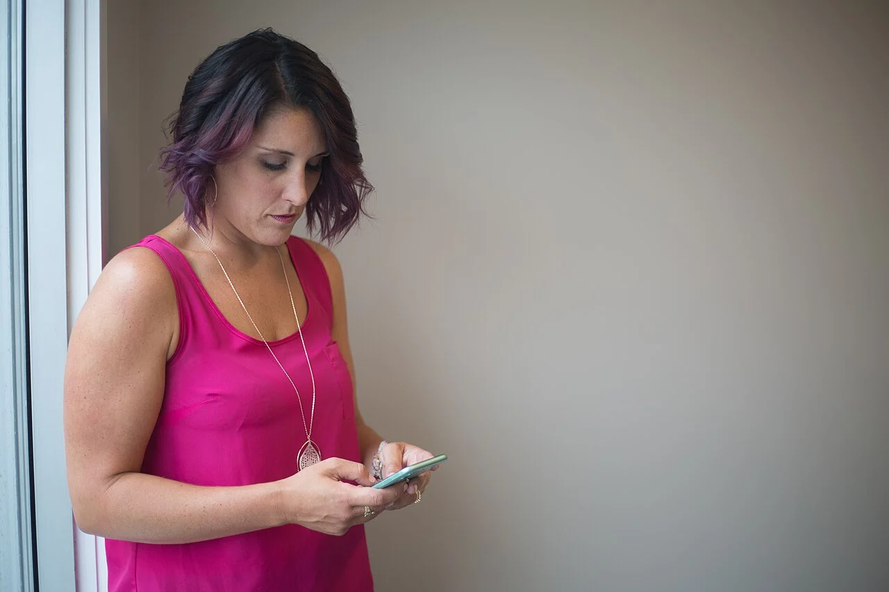 Mulher consultando um smartphone; é importante verificar a autenticidade de promoções recebidas por mensagens