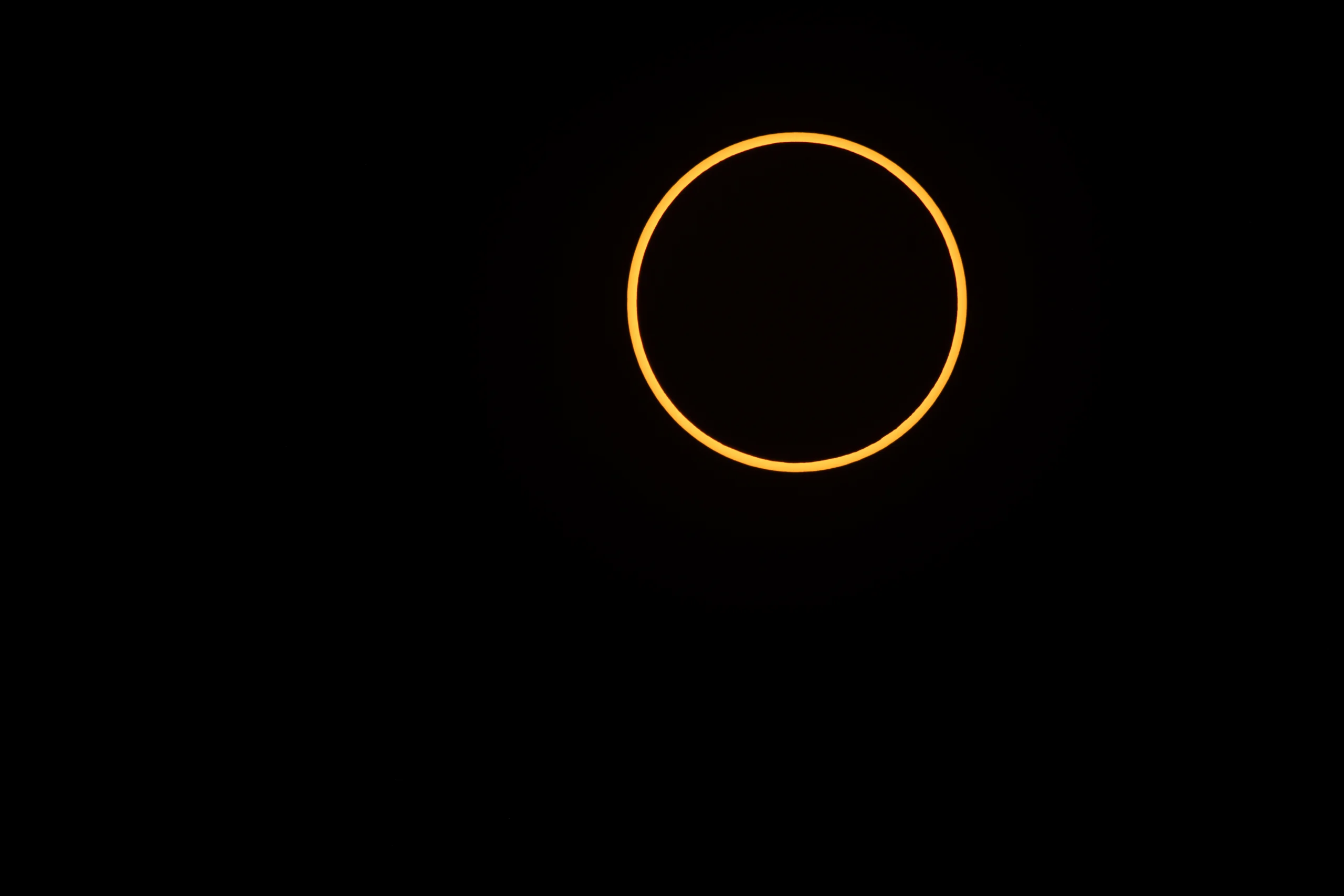 Eclipse solar anular fotografado pela NASA em 2023, com um anel laranja de luz em torno do disco escuro da Lua