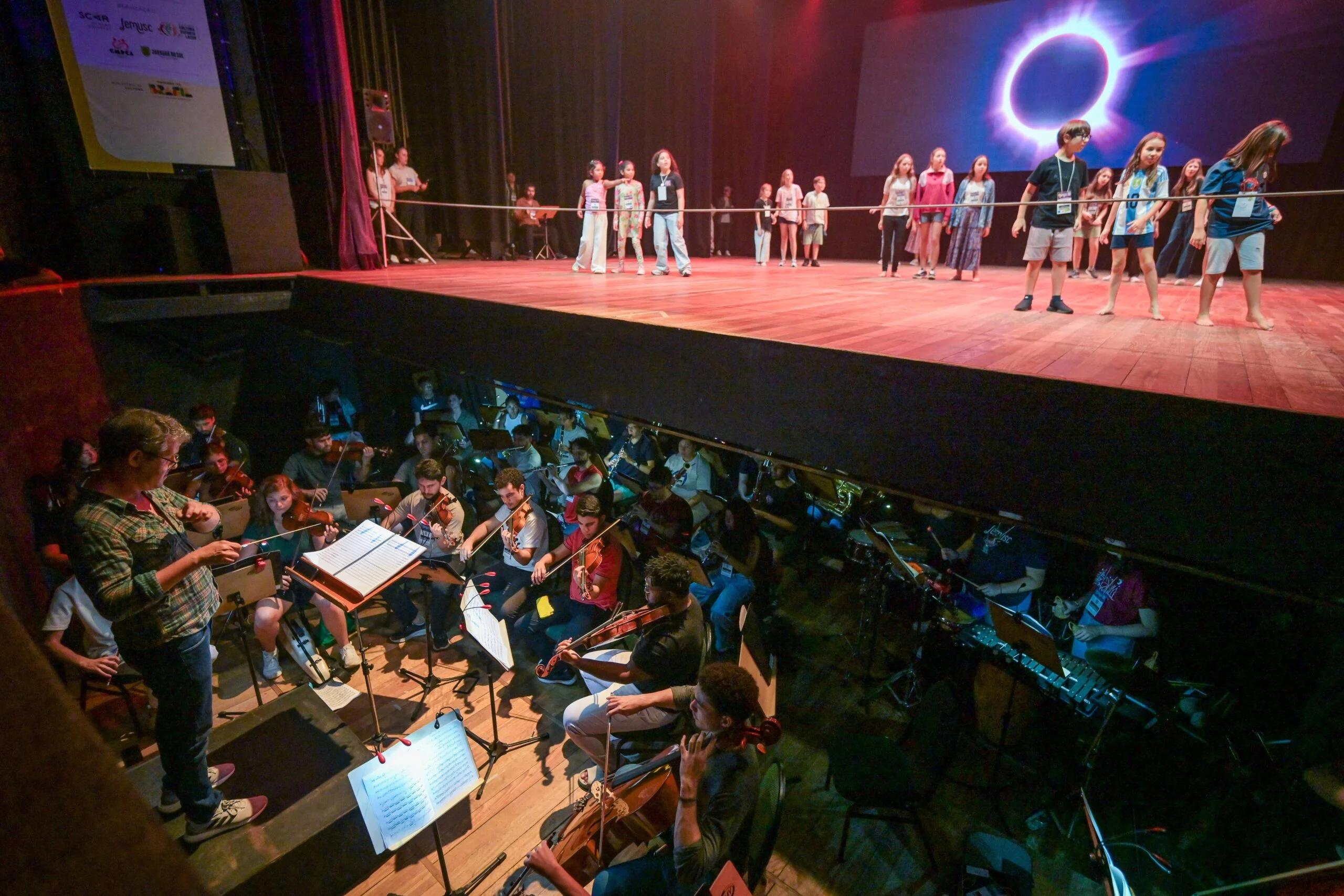 Ensaio da ópera Onheama no Femusc de 2026, com elenco no palco e músicos na orquestra