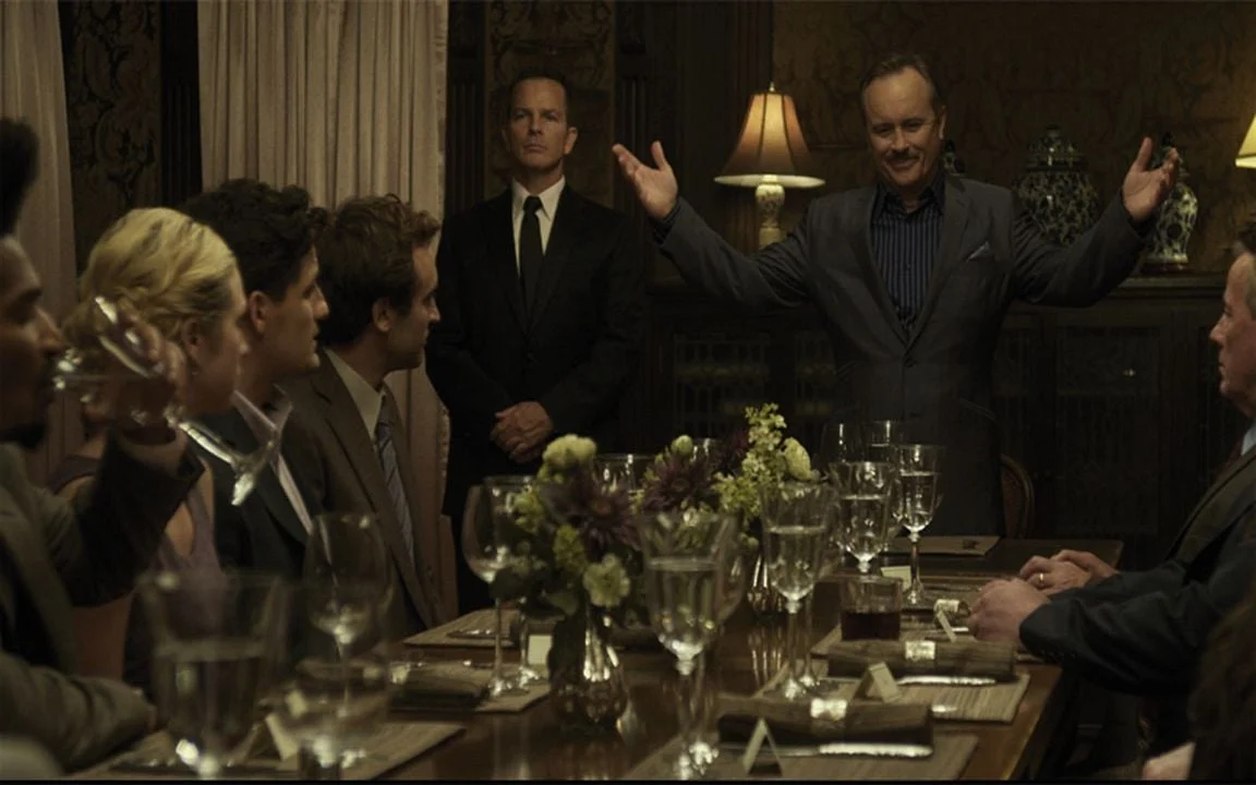 Shepard Lambrick, vivido por Jeffrey Combs, recebe convidados ao redor da mesa de jantar em Would You Rather