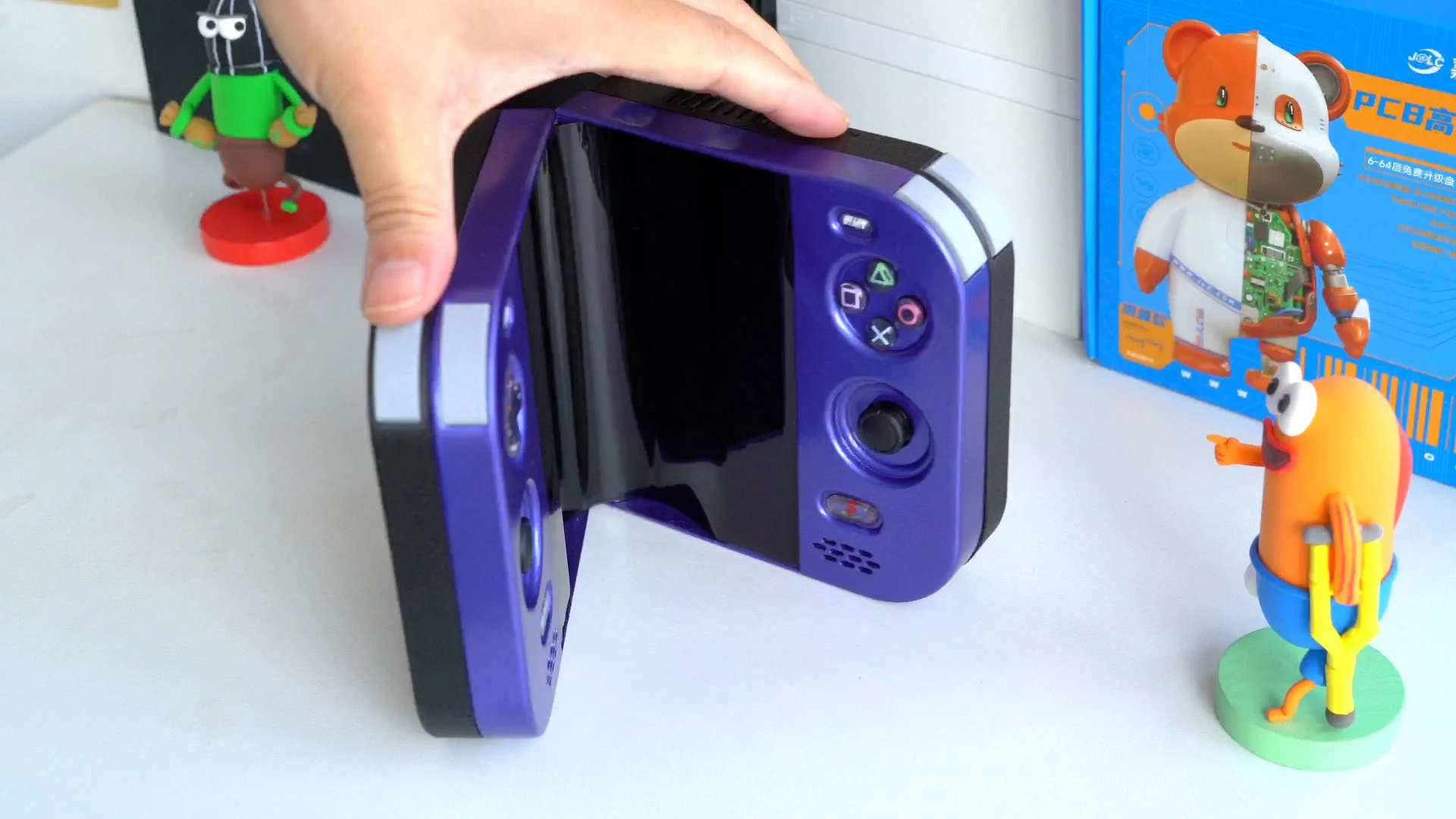PlayStation 2 DUO roxo parcialmente dobrado, com tela flexível curvada no centro e controles nas laterais