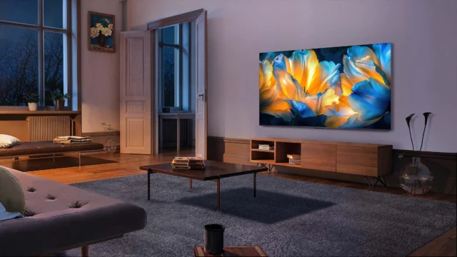 Imagem de divulgação da TCL C6K instalada na parede de uma sala, com flores azuis e amarelas na tela