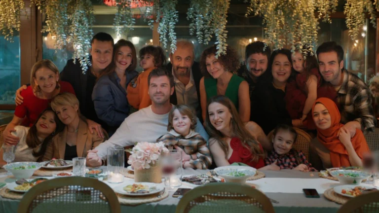 Personagens de Aile reunidos à mesa, com bolo, crianças e os protagonistas no encerramento