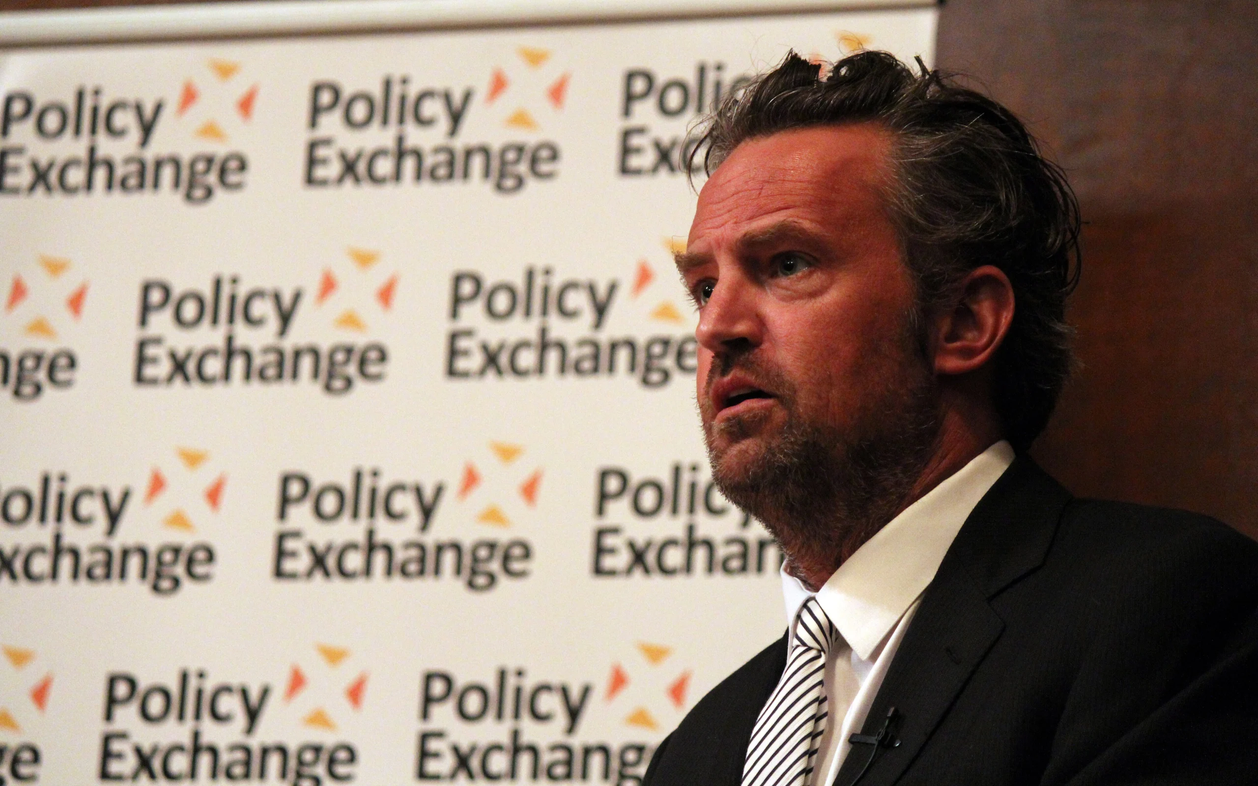 Matthew Perry fala durante encontro do Policy Exchange sobre justiça e apoio a pessoas com problemas relacionados a drogas em dezembro de 2013