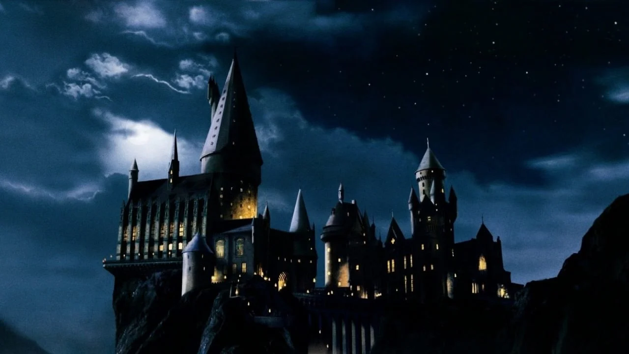 Castelo de Hogwarts à noite, iluminado nas janelas sob um céu estrelado