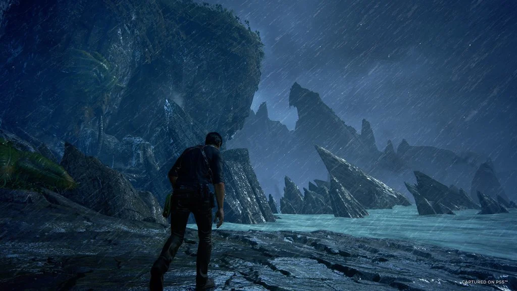 Nathan Drake caminha por uma costa rochosa em Uncharted 4