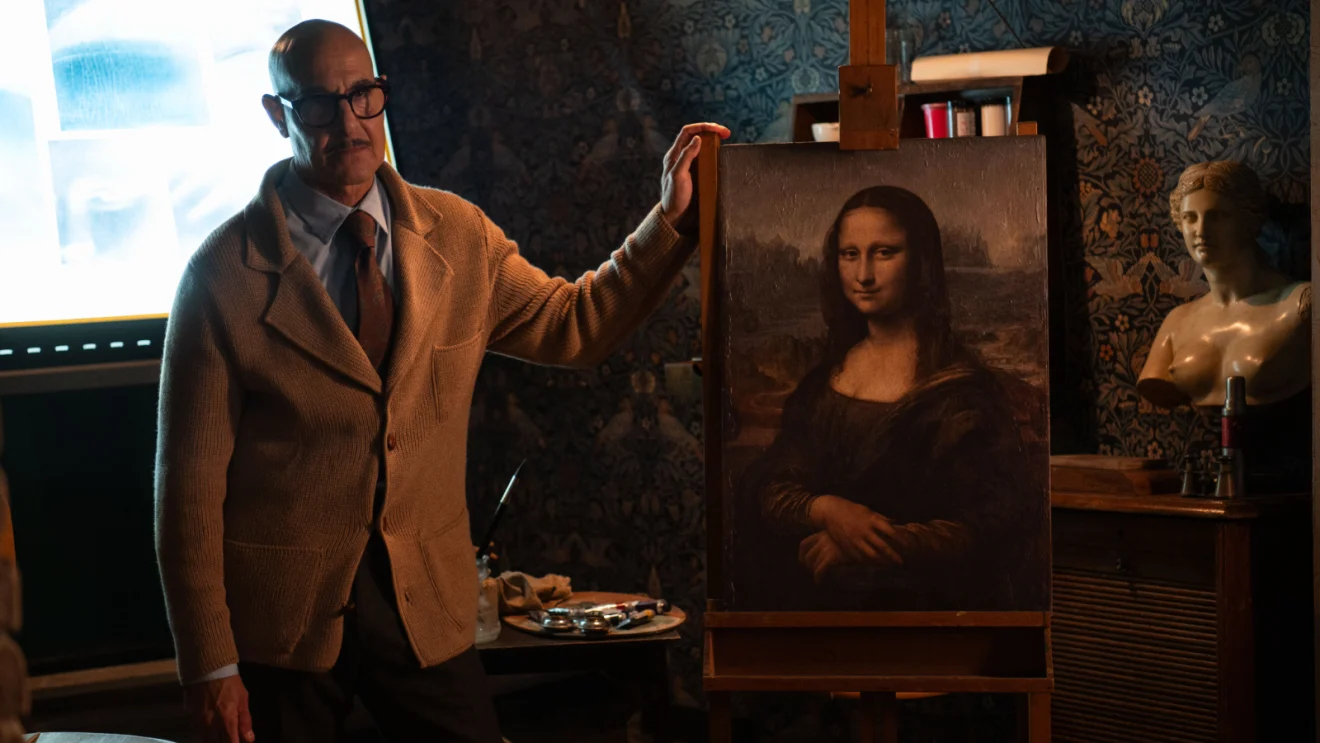 Roger, interpretado por Stanley Tucci, posa ao lado de uma reprodução da Mona Lisa em Masterplan