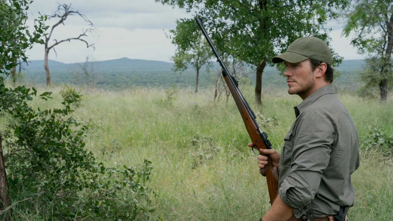 James Reece, vivido por Chris Pratt, segura um rifle em uma paisagem aberta em A Lista Terminal 2