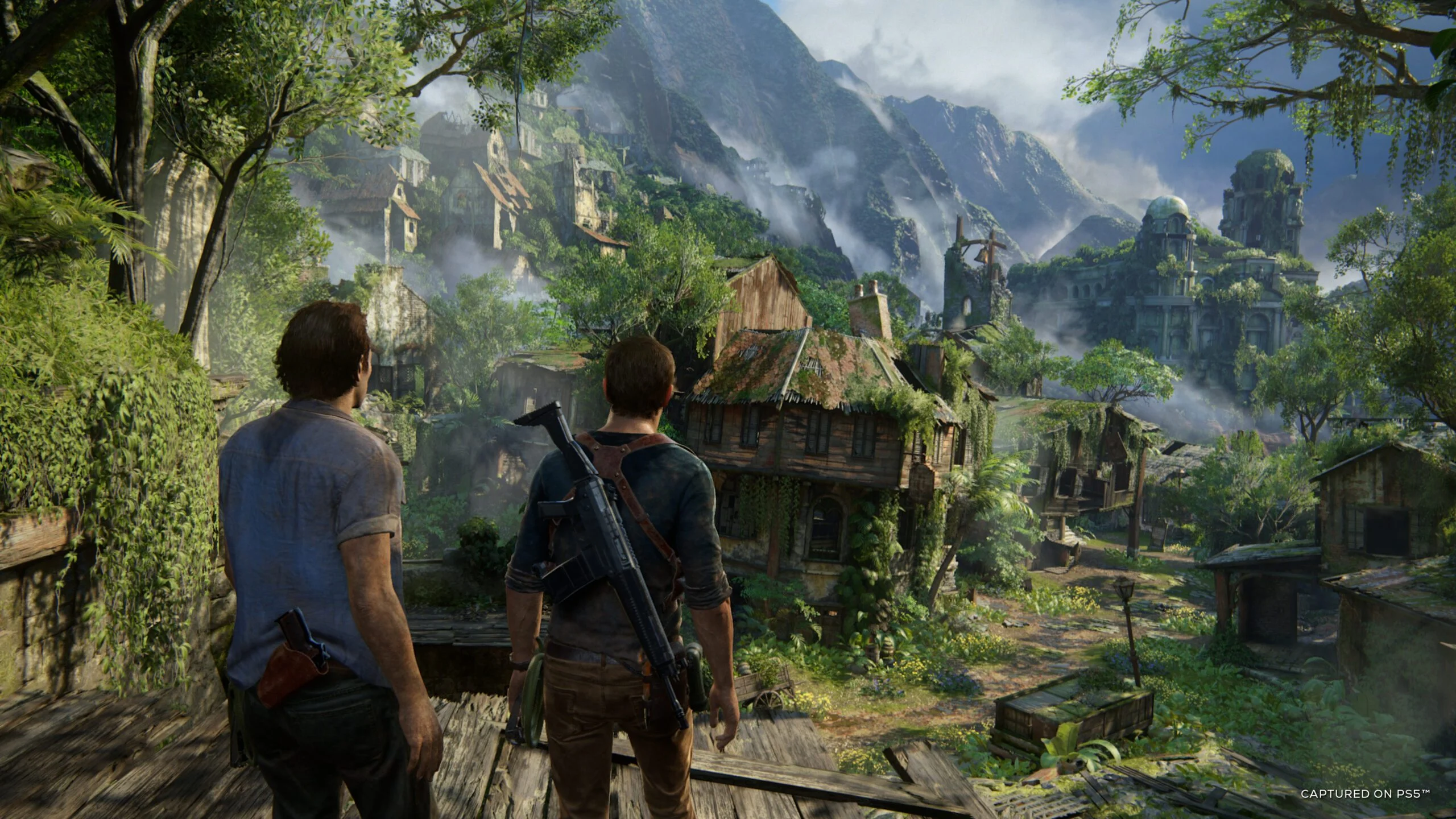Nathan Drake e Sam Drake observam uma vila cercada por montanhas em Uncharted 4 A Thief's End