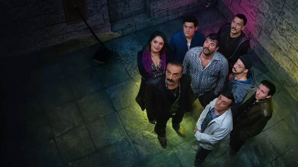 Asım Noyan e integrantes de sua equipe observam algo em uma sala subterrânea na série turca Asim, O Vigarista, da Netflix