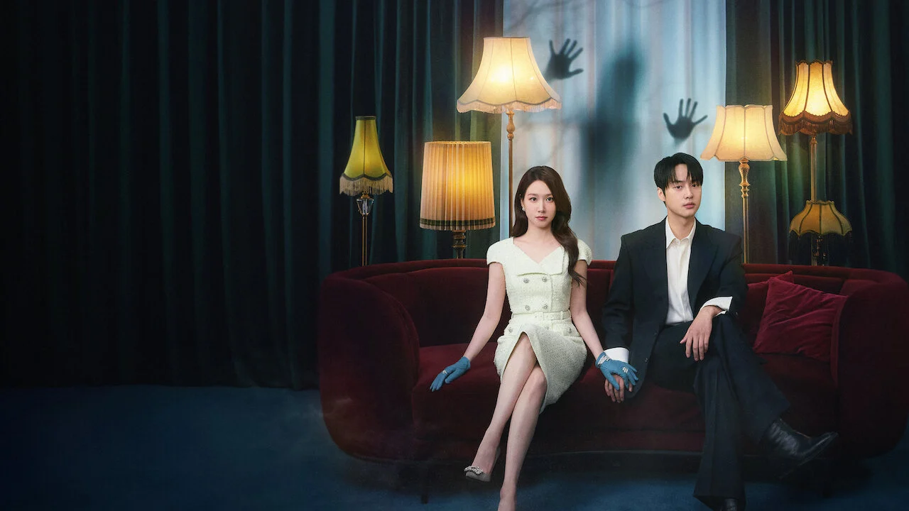 Park Eun-bin e Yang Se-jong sentados em um sofá em Assustadoramente Apaixonados, com mãos fantasmagóricas ao fundo