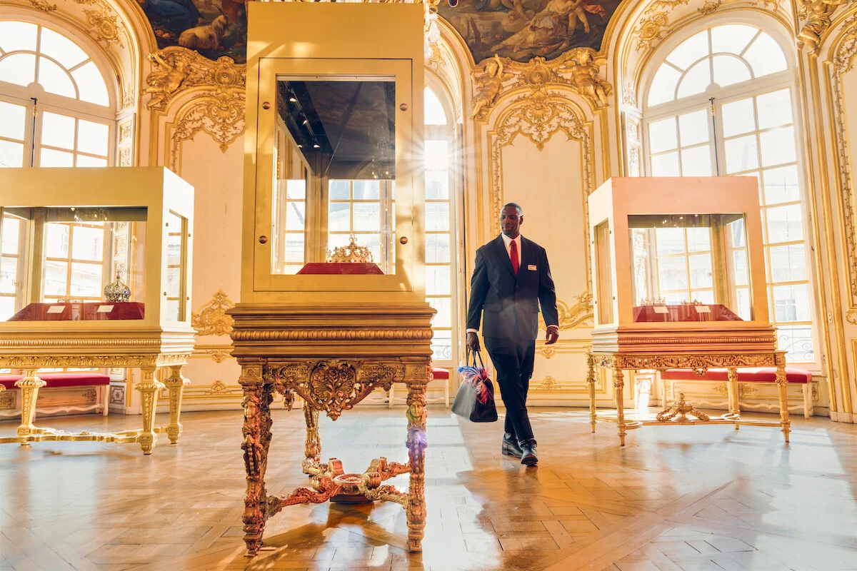 Assane Diop caminha por salão de museu com vitrines de peças históricas em Lupin Parte 4