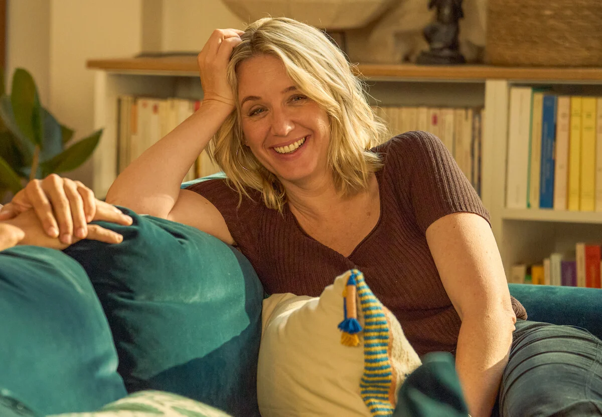 Claire Laurent, interpretada por Ludivine Sagnier, aparece sorrindo sentada em um sofá na parte 4 de Lupin.