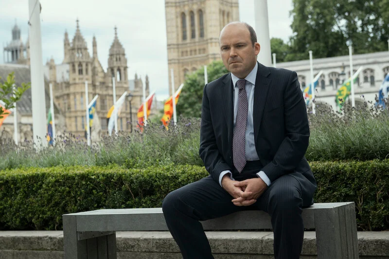 Primeiro-ministro Nicol Trowbridge, interpretado por Rory Kinnear, sentado diante do Parlamento britânico