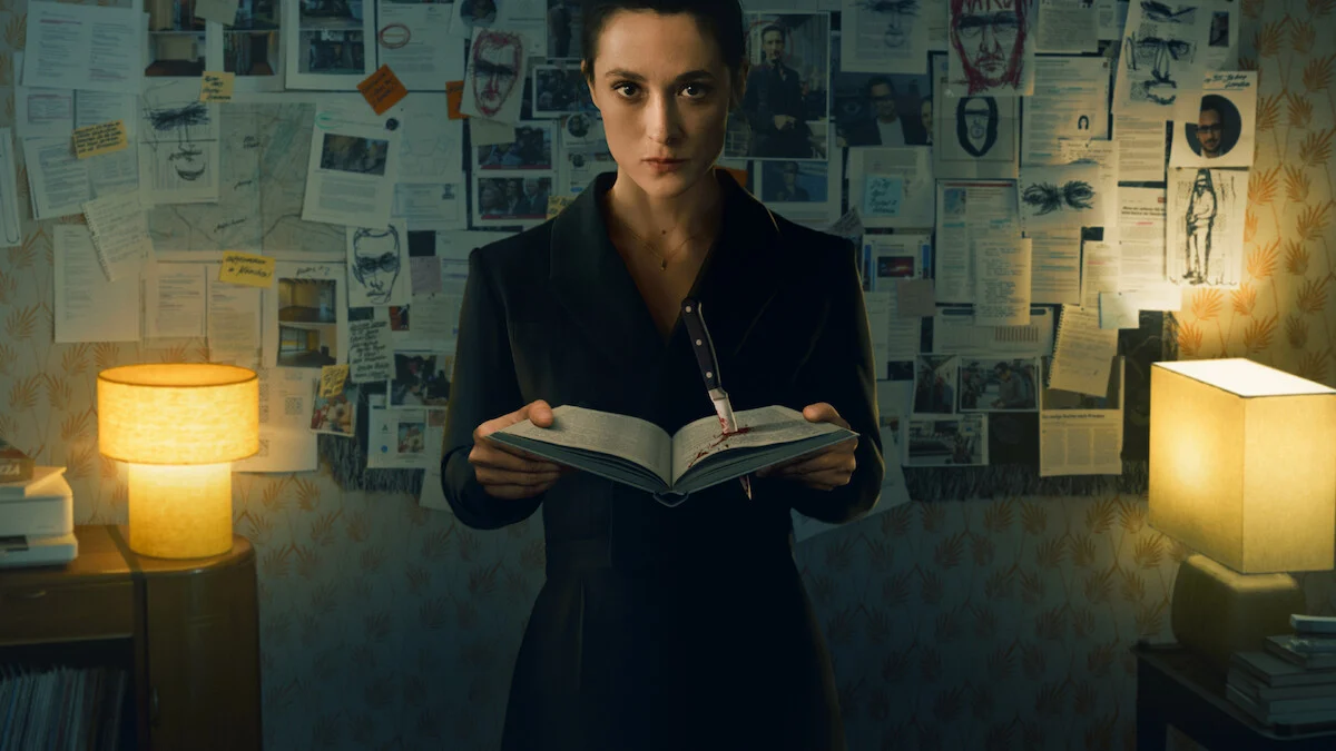 Imagem de divulgação de Armadilha mostra uma mulher com um livro aberto diante de uma parede de recortes