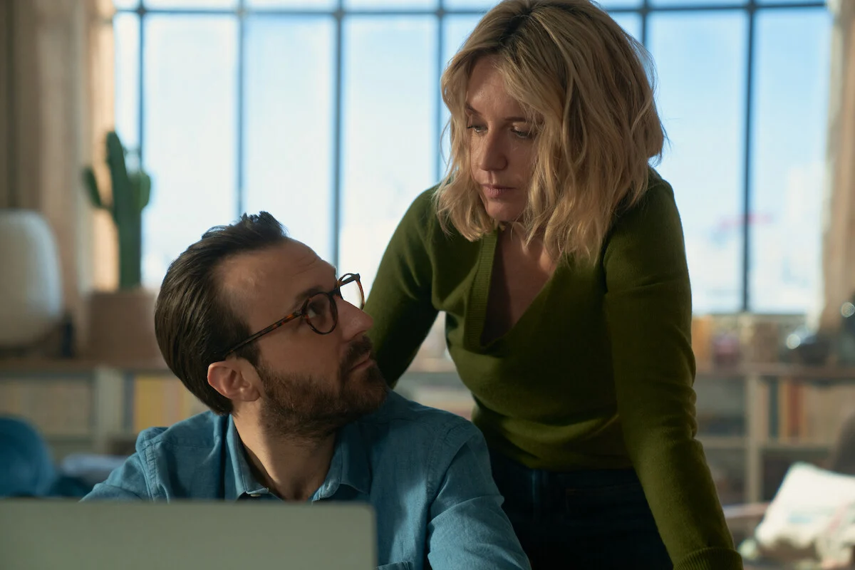 Ludivine Sagnier como Claire Laurent se aproxima de Antoine Gouy como Benjamin Férel diante de um notebook em Lupin Parte 4