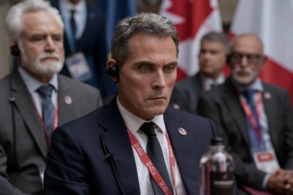 Hal Wyler, interpretado por Rufus Sewell, aparece na reunião do G7 em A Diplomata