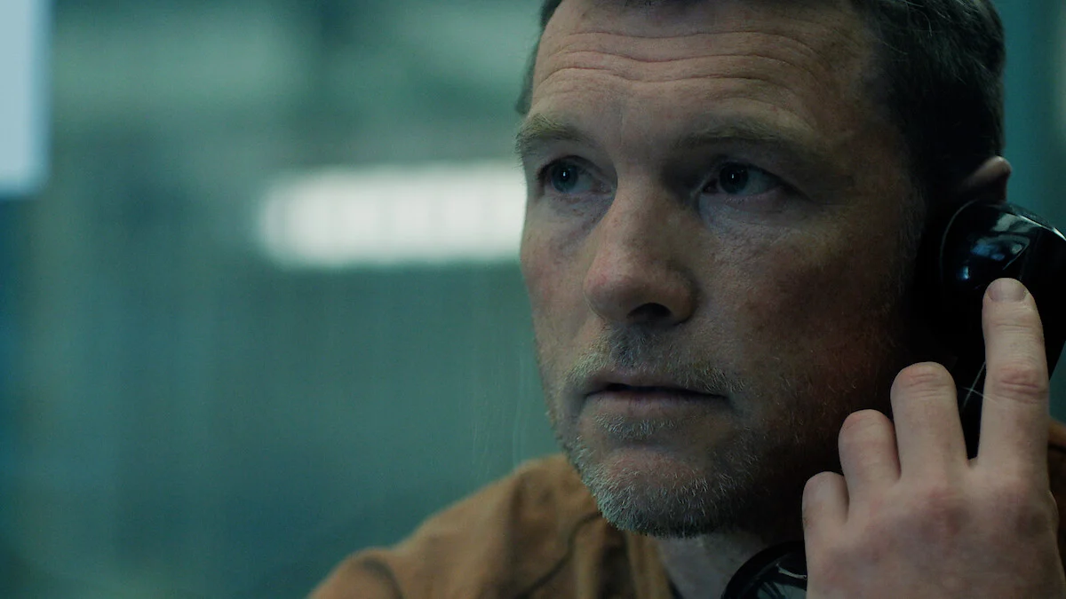 Sam Worthington como David Burroughs falando ao telefone na prisão em Eu Vou Te Encontrar