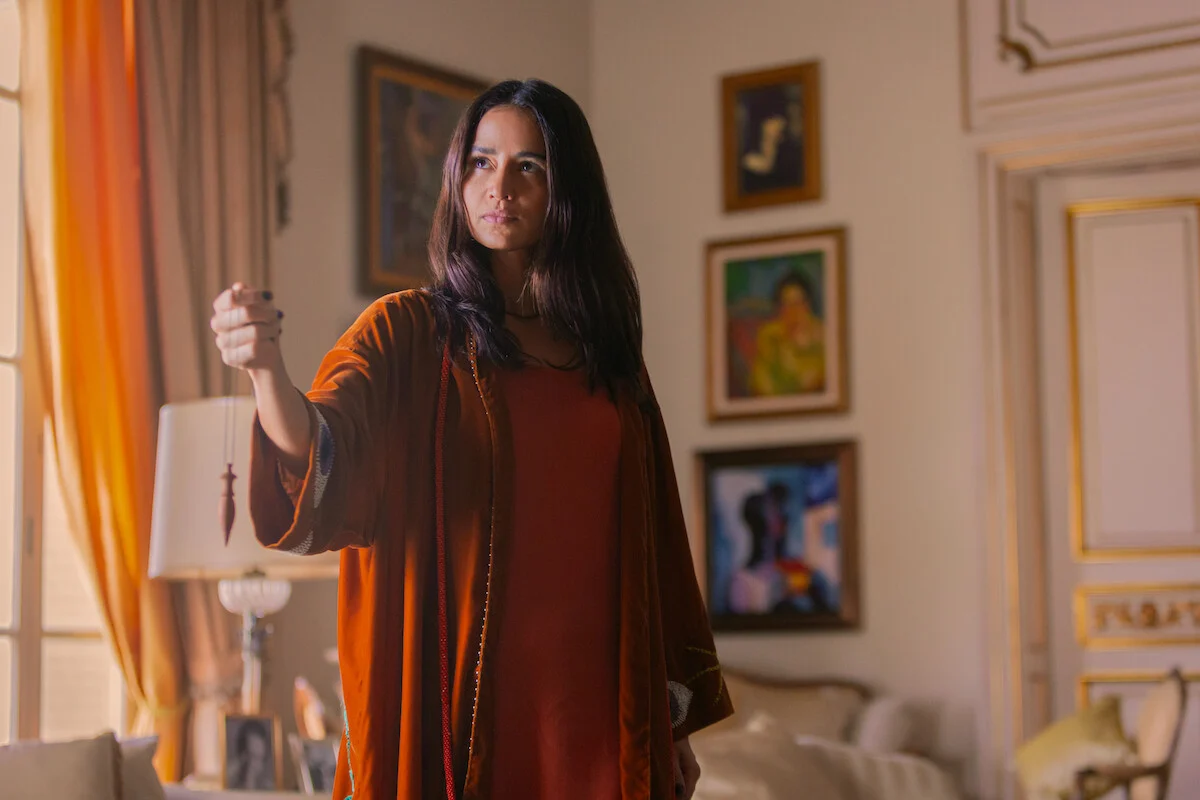 Nanda Costta interpreta Irina Petrov, a falsa terapeuta espiritual de Dom de Iludir, segurando um pêndulo