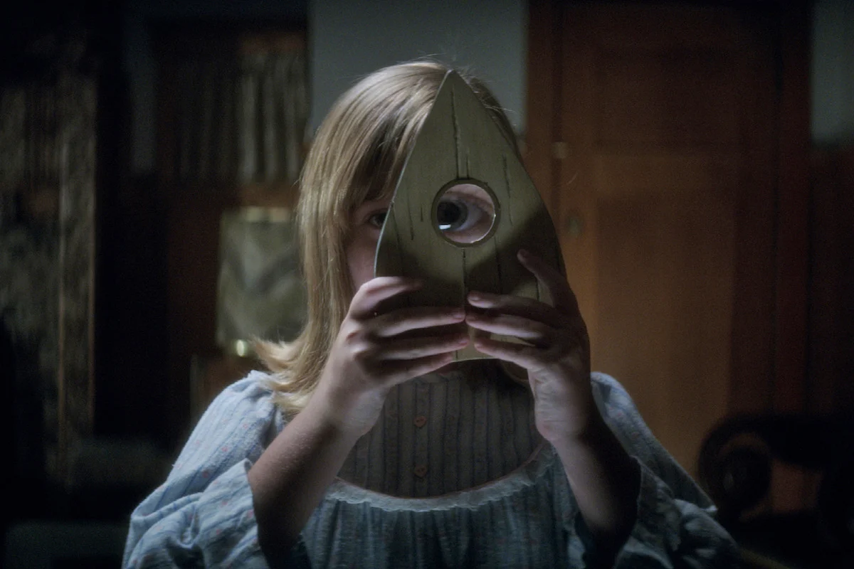 Doris segura uma peça do tabuleiro em Ouija Origem do Mal