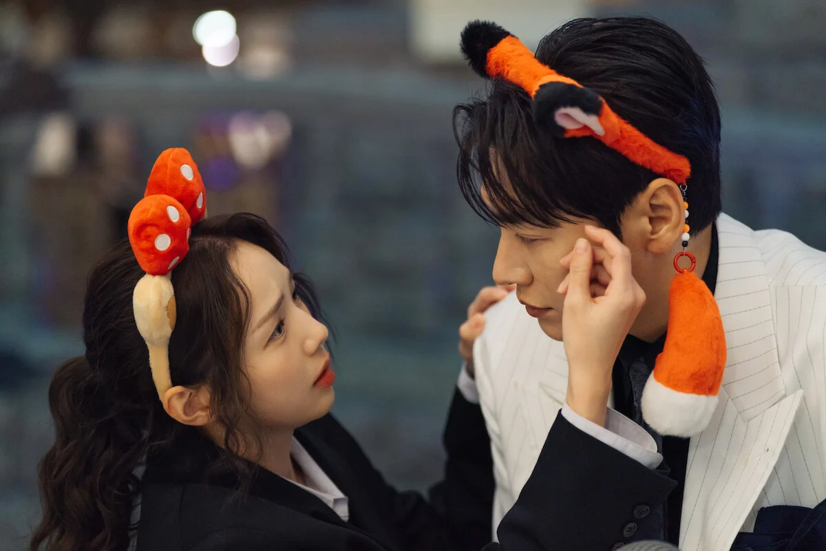 Na Bo-bae toca o rosto de Baek Ho-rang durante um passeio usando acessórios de fantasia