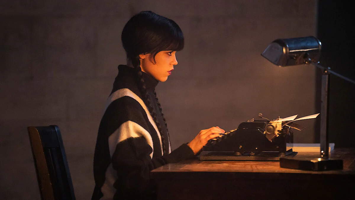 Jenna Ortega como Wandinha Addams escrevendo em uma máquina de escrever em imagem da terceira temporada