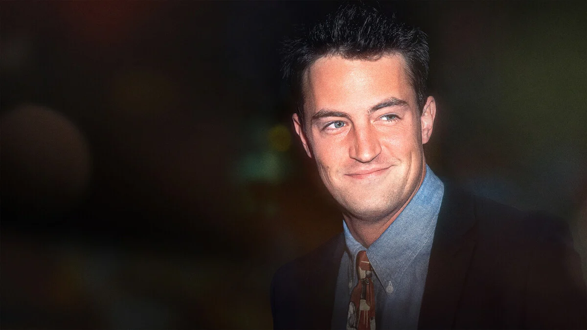 Matthew Perry jovem, usando terno e gravata, em imagem de arquivo divulgada para o documentário Aquele Sobre Matthew Perry