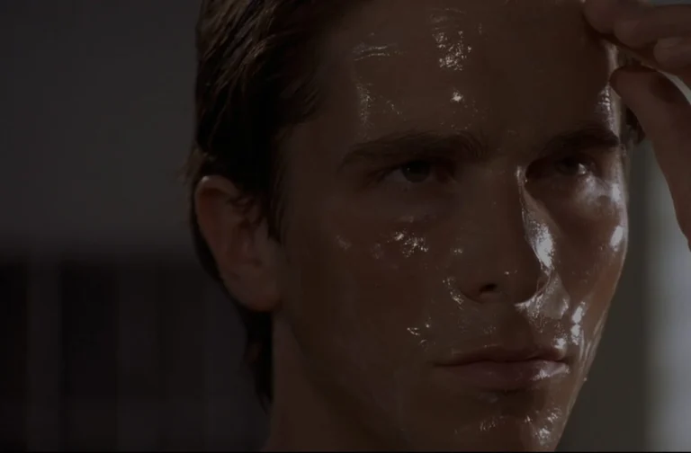 Christian Bale interpreta Patrick Bateman em close de Psicopata Americano, com o rosto coberto por máscara facial