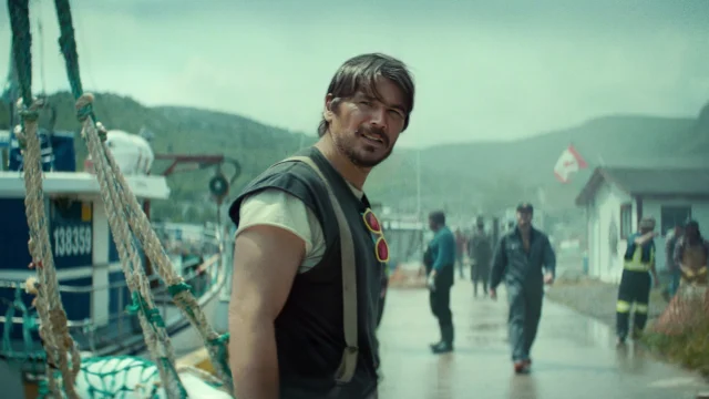 Josh Hartnett como Calvin Penney no porto, com a costa e moradores ao fundo em Profundezas