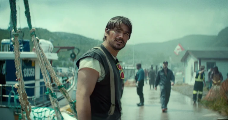Josh Hartnett como Calvin Penney no porto, com a costa e moradores ao fundo em Profundezas
