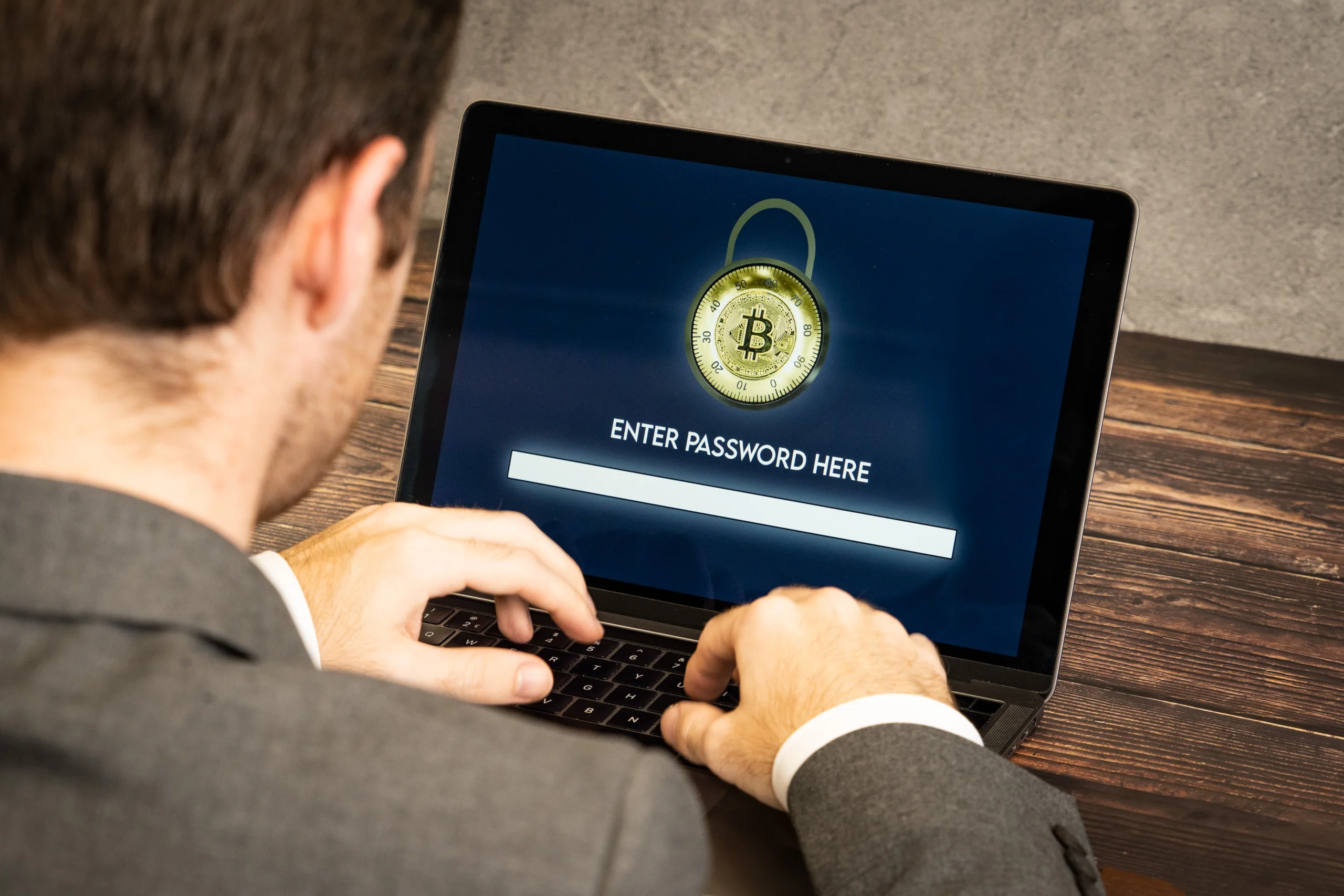 Pessoa digitando uma senha em notebook com símbolo de criptomoeda e cadeado na tela