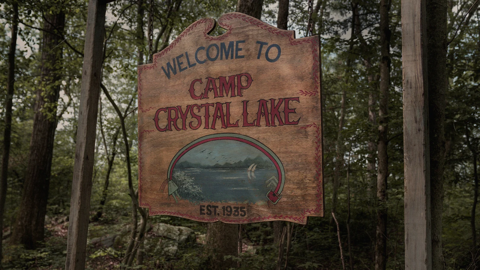 Placa de madeira de entrada do Camp Crystal Lake entre árvores.